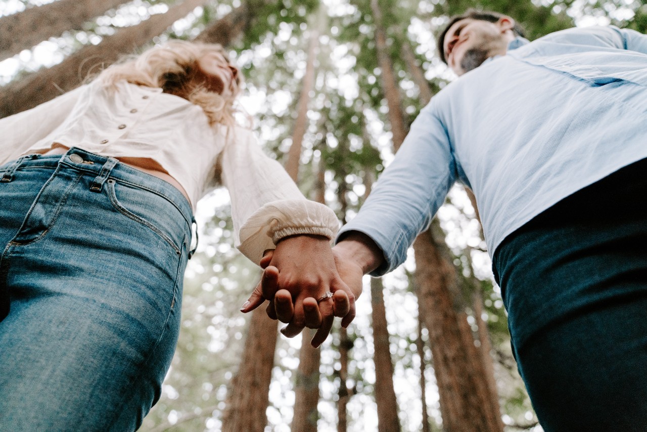 couple holding hands in forest