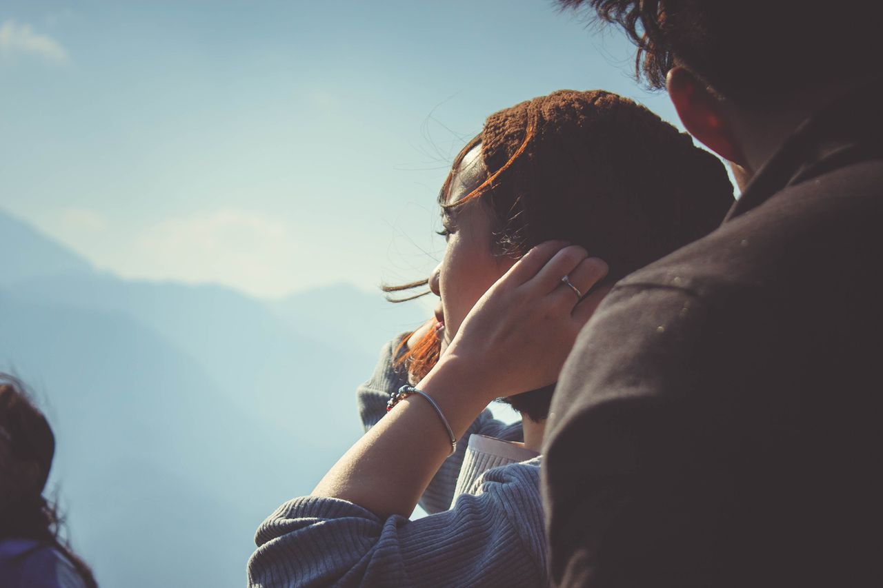 Woman wearing a gemstone bracelet as she looks out from the top of a mountain with her tour group