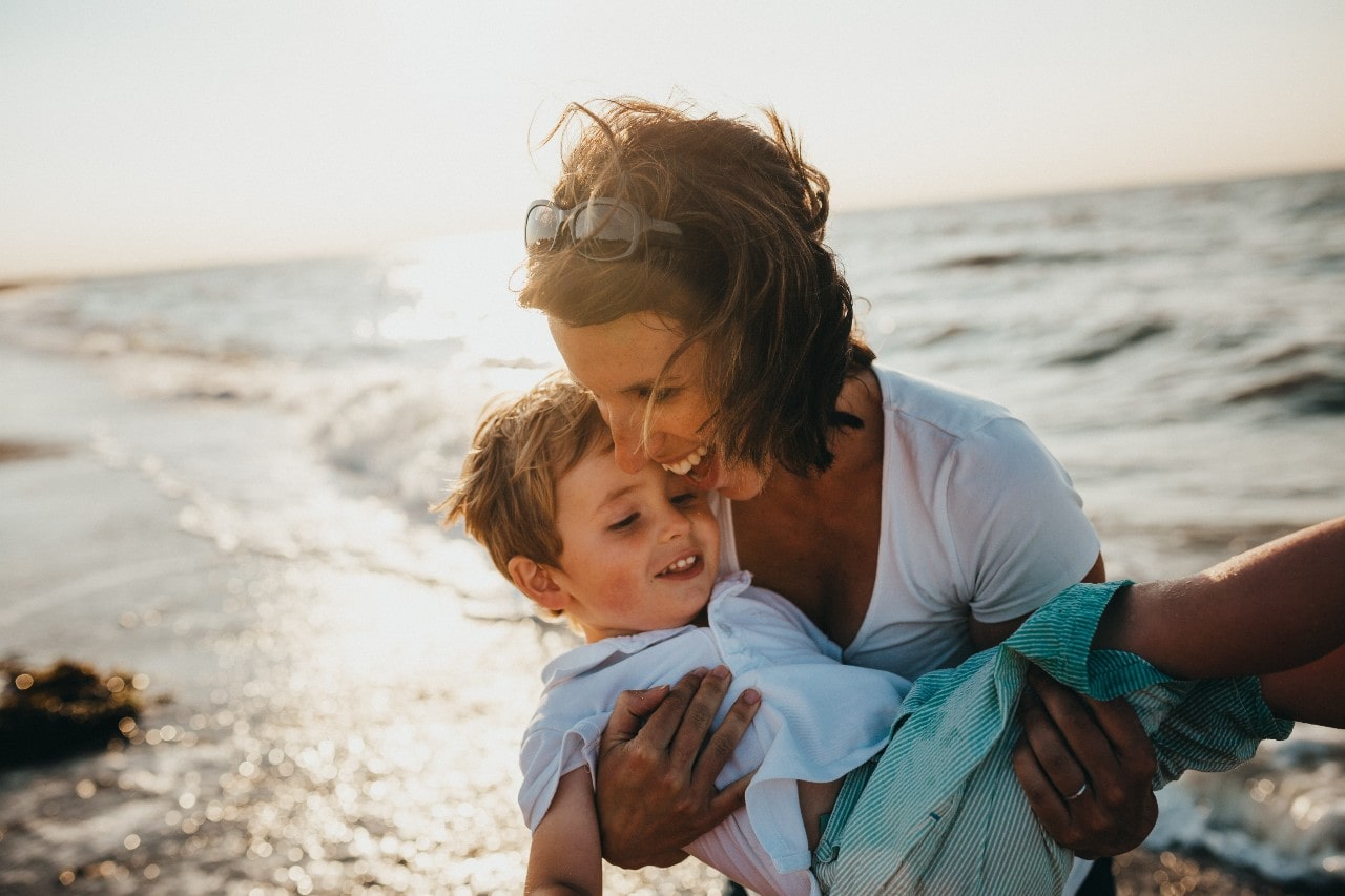 A mother plays with her son at the beach