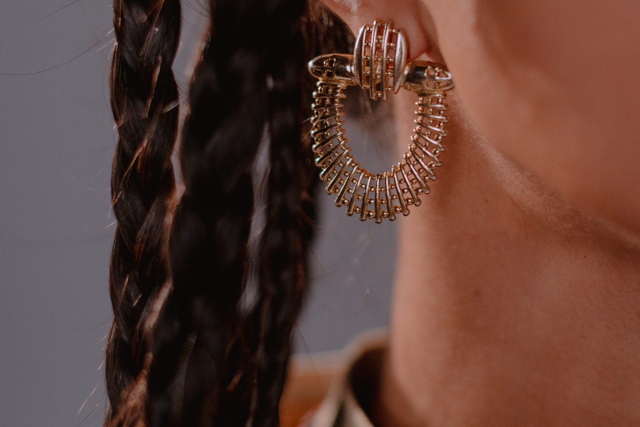 Close-up image of a woman’s ear wearing an elaborate metal earring