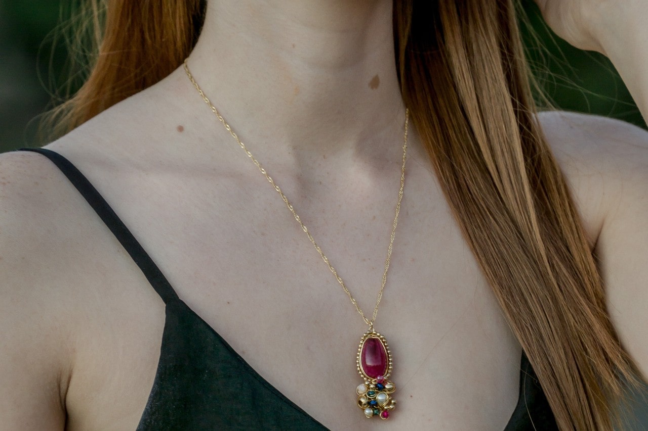 Woman wearing a yellow gold necklace with various gemstones