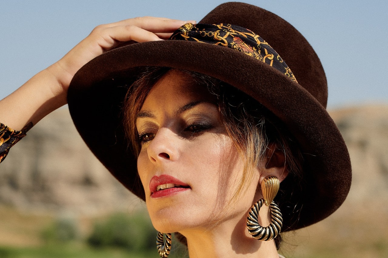 Elegant lady holding her hat whilst showing off her white gold earrings