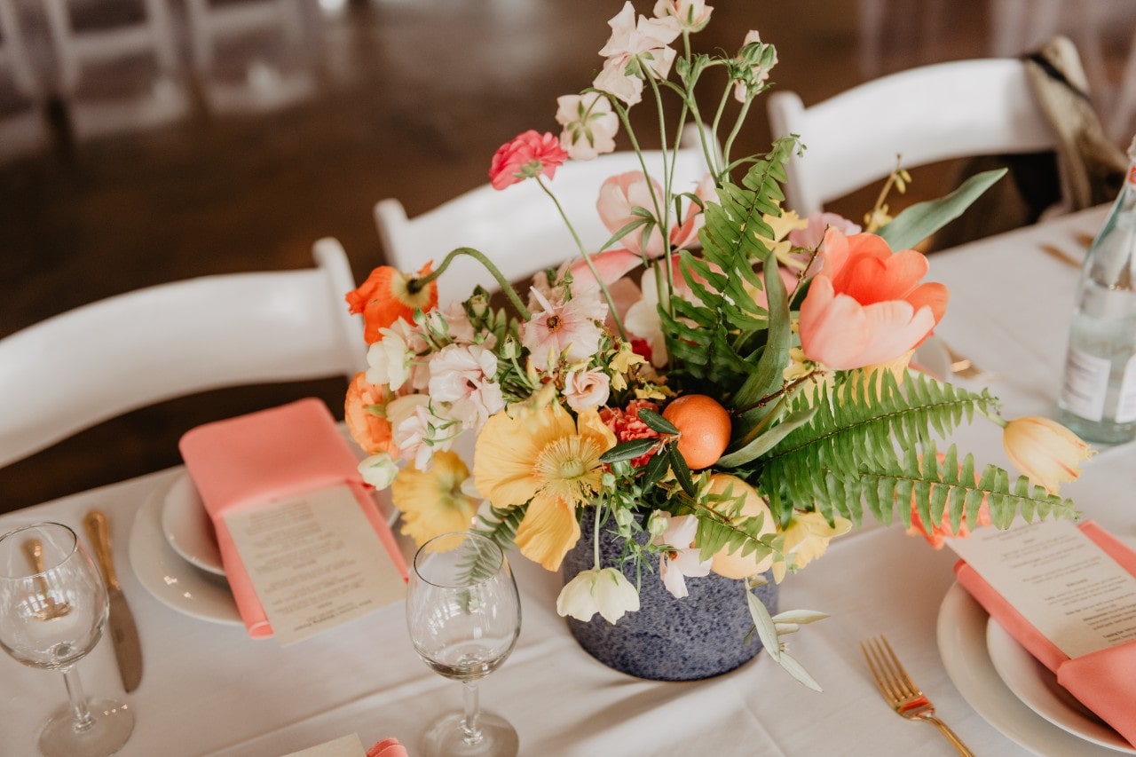 A wildflower centerpiece on a table with white and bright pink accents