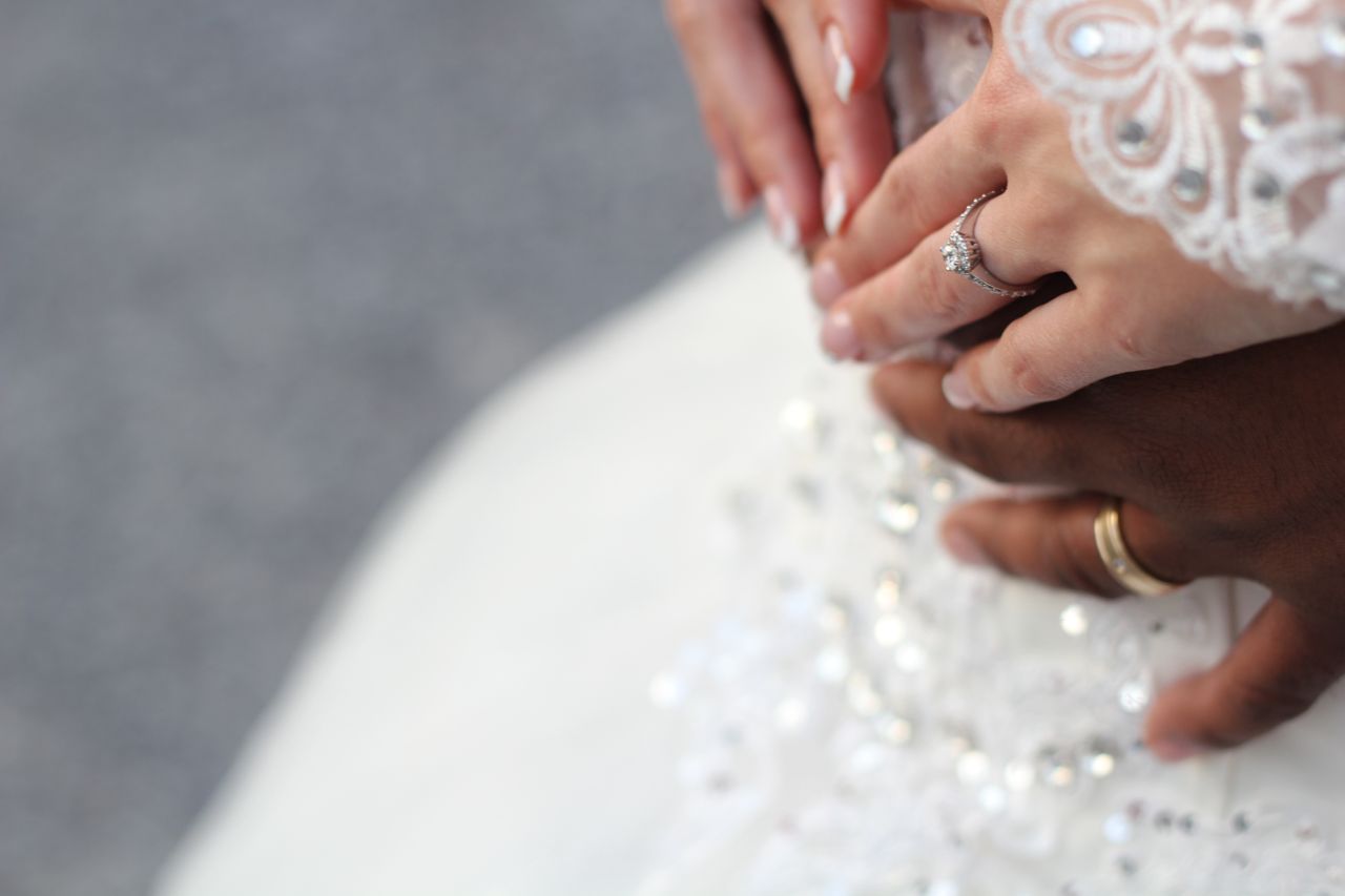 A newly-wed couple embrace, showing off their bridal jewelry