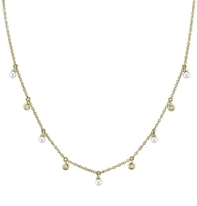 a pearl and diamond station necklace made with yellow gold.