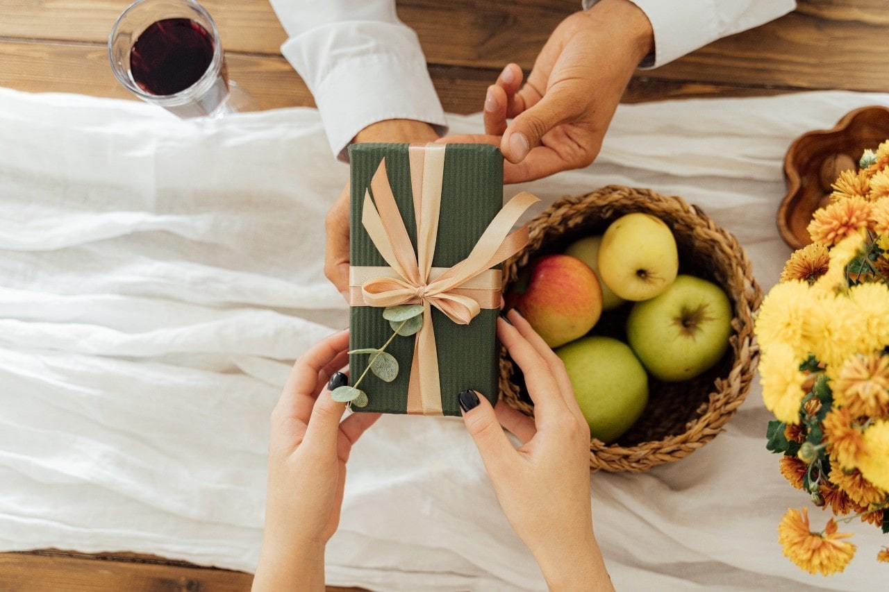 A man hands his date a green wrapped box during their St. Patty Day celebration.