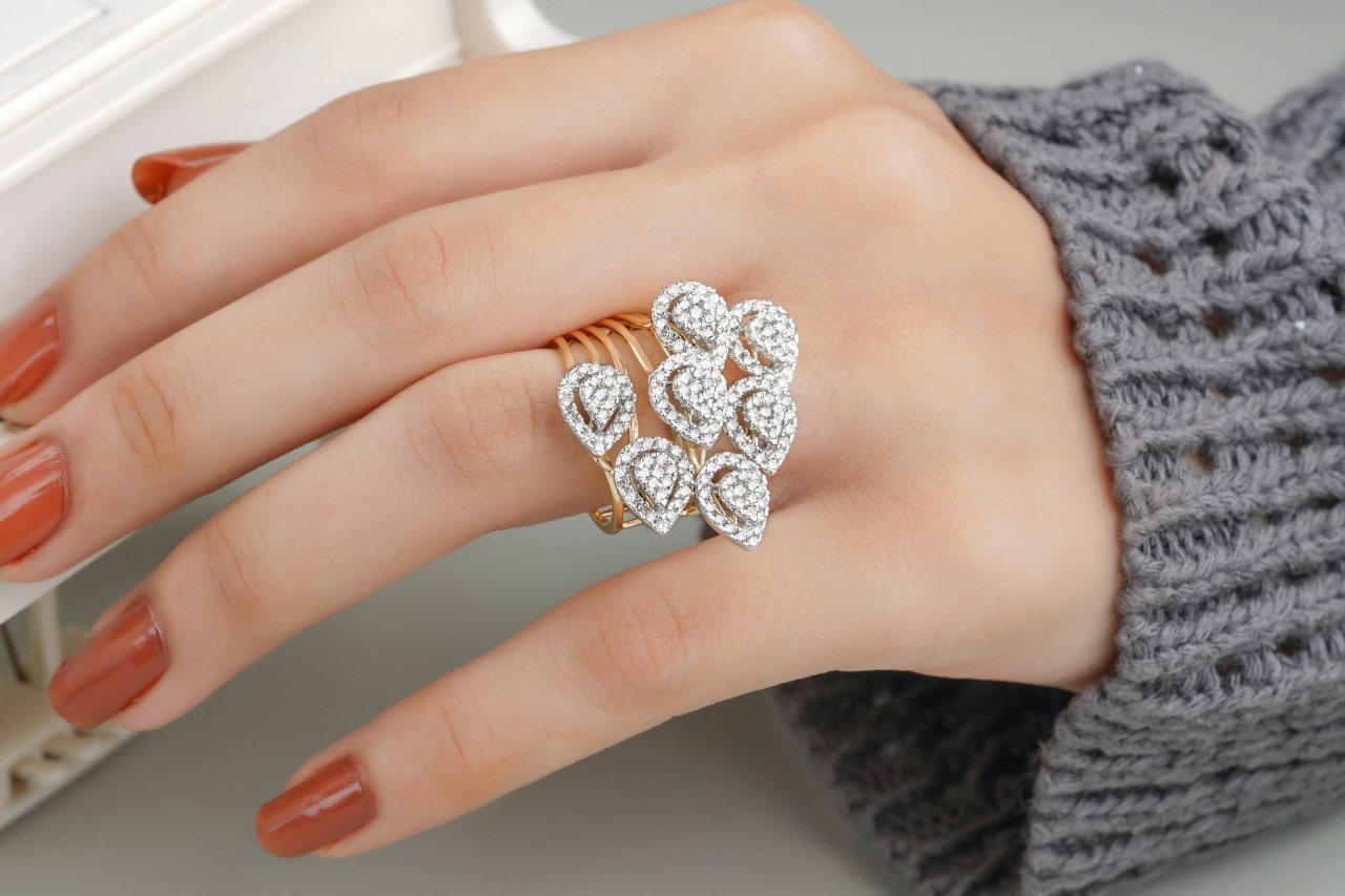 close up image of a woman’s hand wearing a large, mixed metal fashion ring