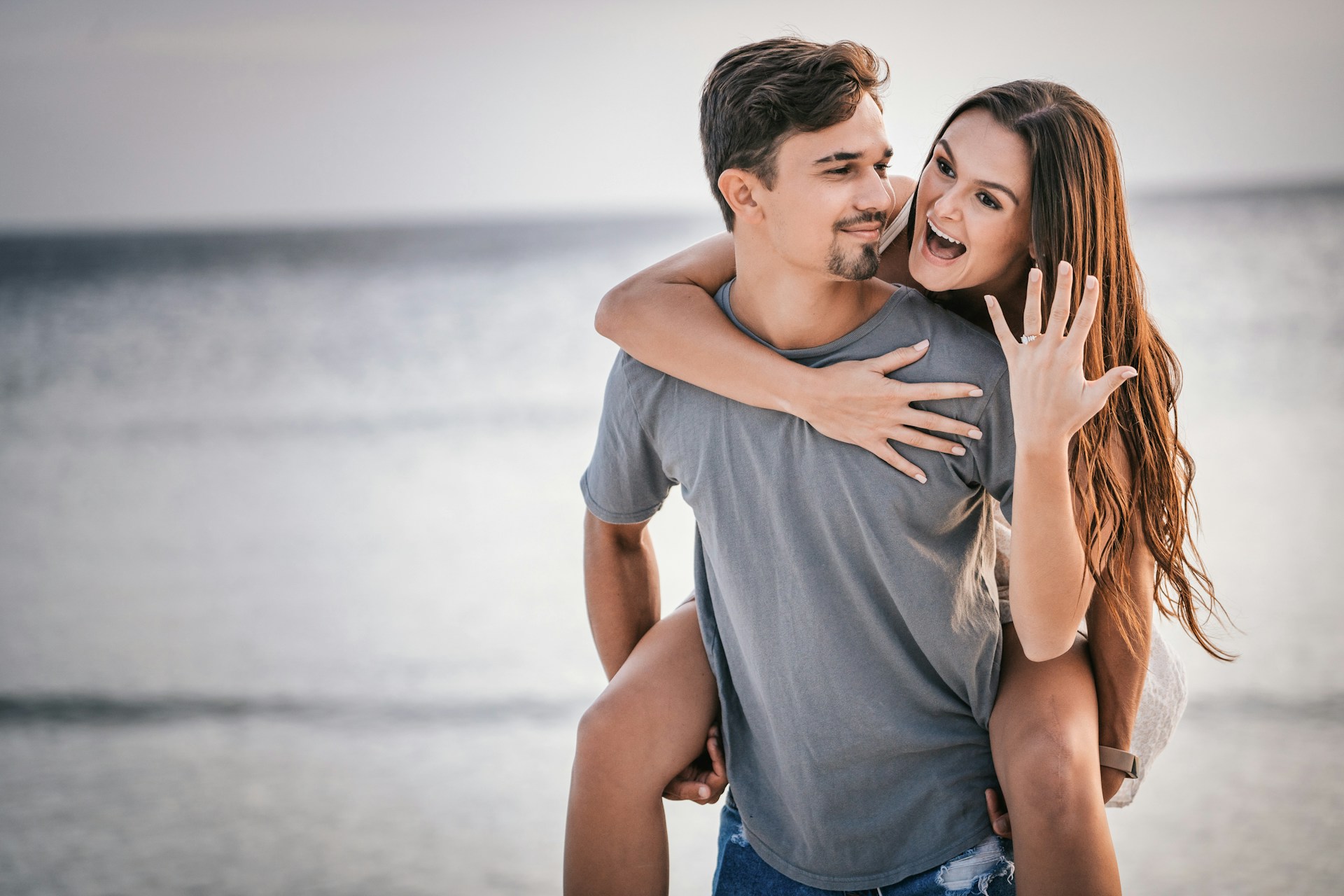 a lady wearing an engagement ring, smiling while riding on a man’s back