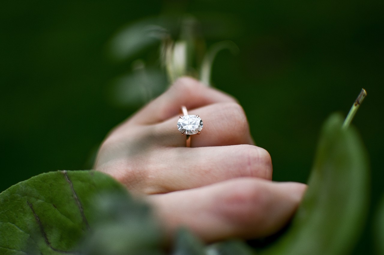 a woman’s hand holding a bouquet and wearing a simple engagement ring