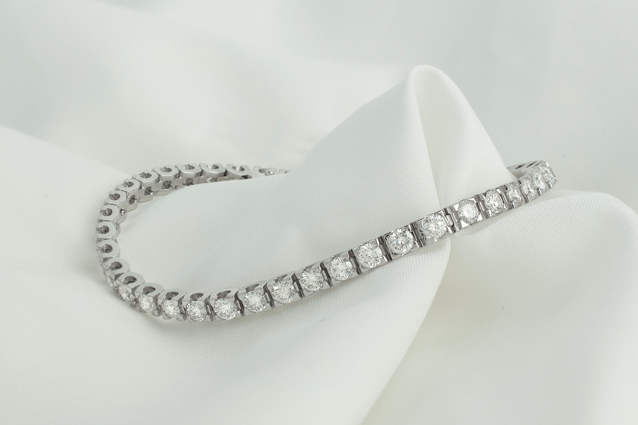 a white gold diamond tennis bracelet on a piece of white fabric