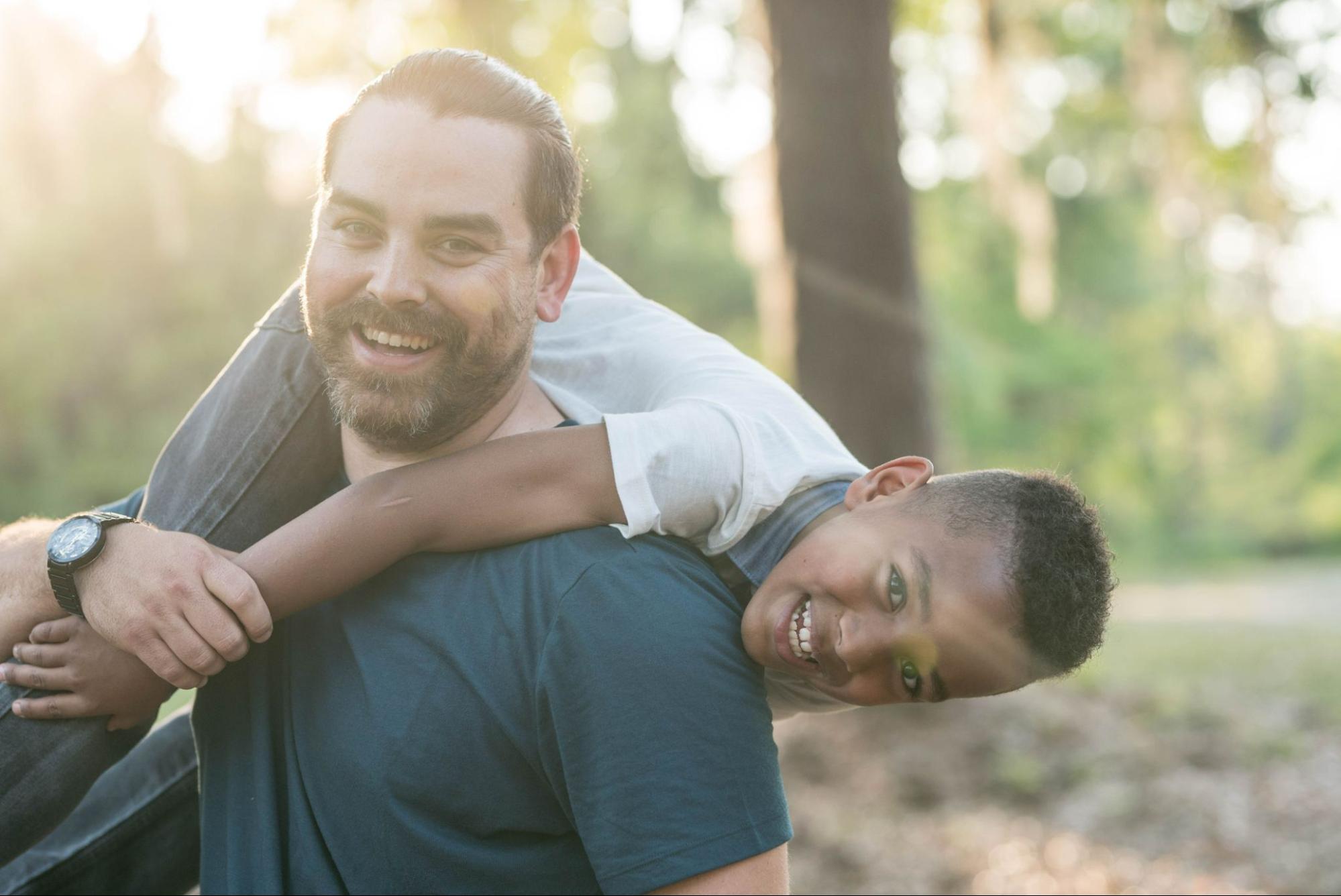 A father plays with his young son in a park.