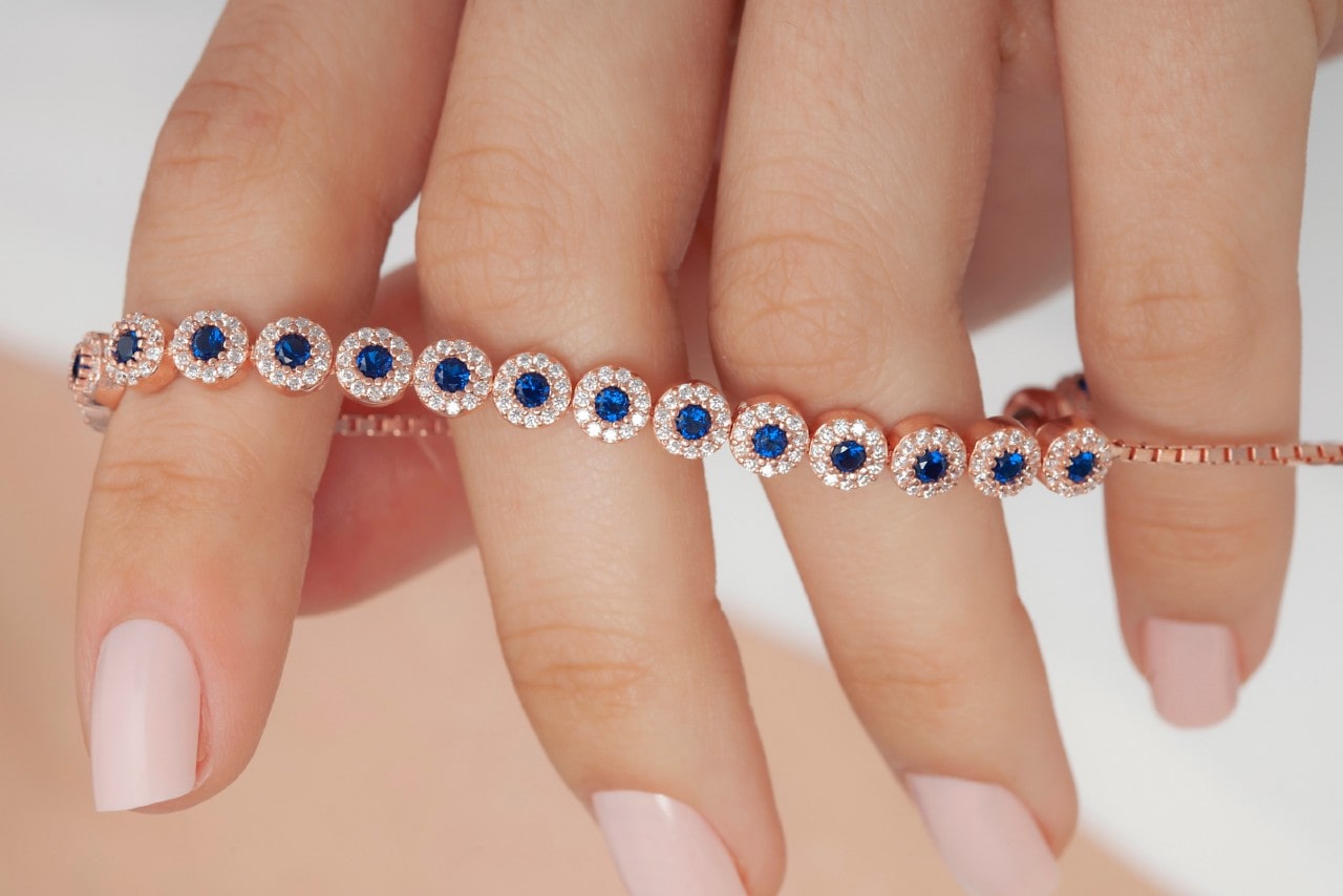 A close-up of a woman’s hand with a sapphire and diamond bracelet draped around her fingers.