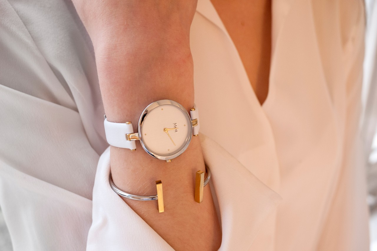 A close-up of a woman wearing a simple yet elegant bracelet paired with a simple wristwatch.