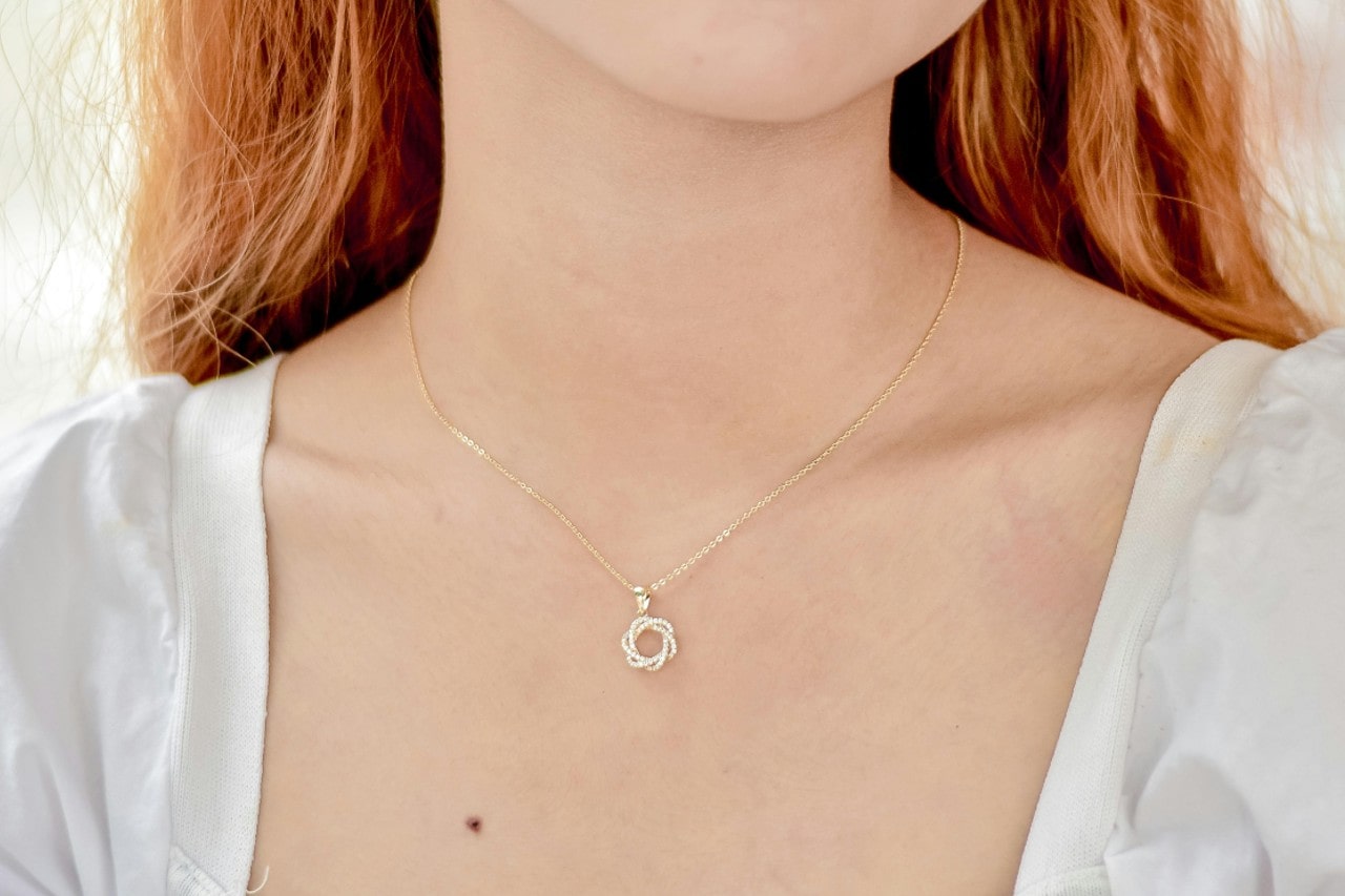 A close-up of a young woman wearing a simple yet elegant pendant necklace.