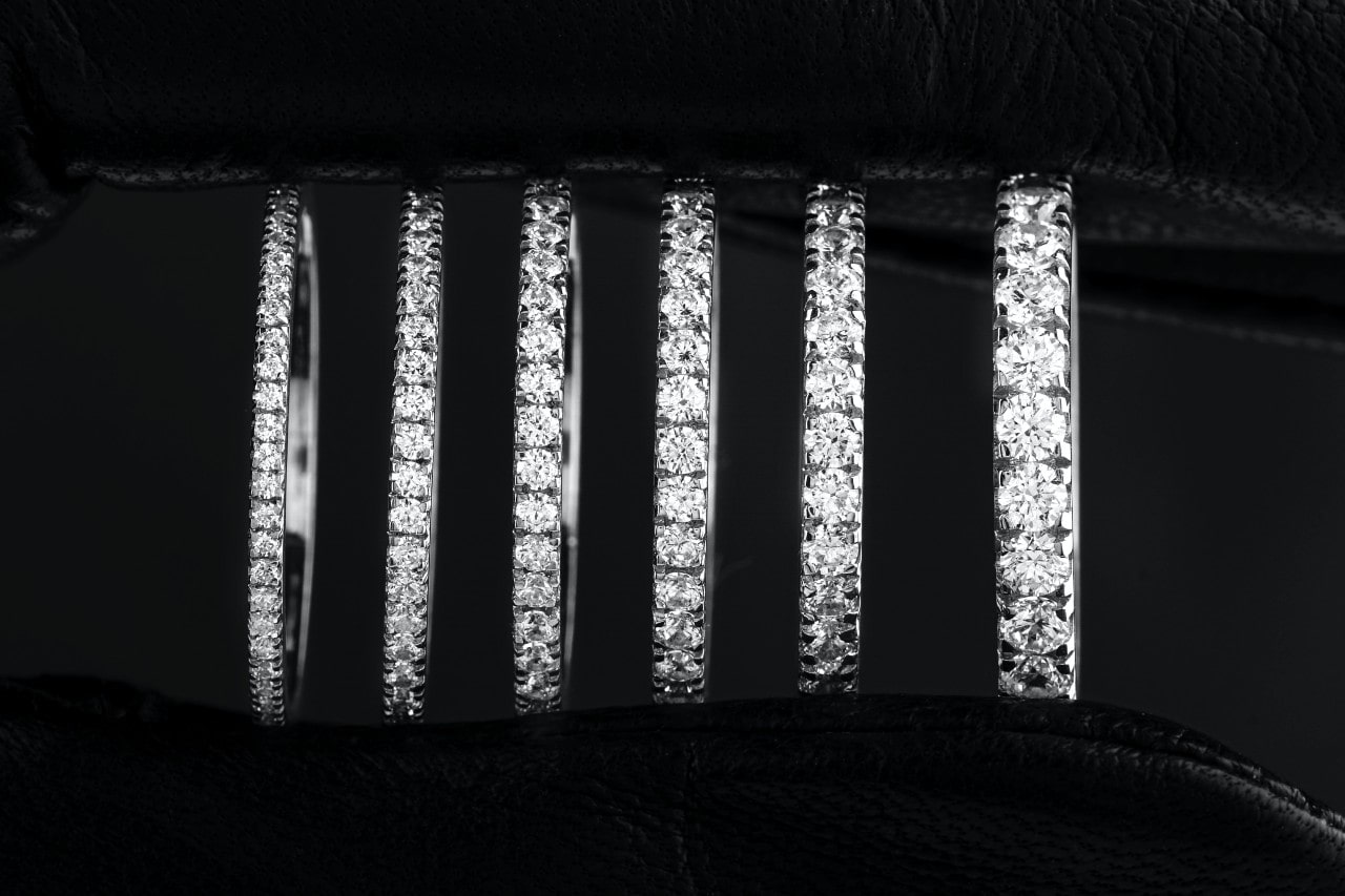 A close-up of six diamond wedding bands in a line, in ascending order of diamond size.