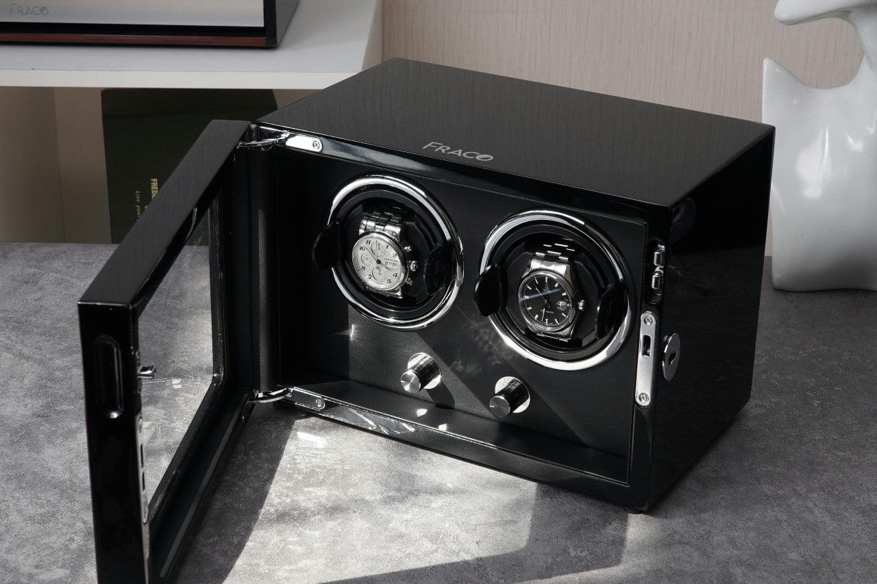 An open, black, glossy Fraco dual-watch winder box with two automatic watches.