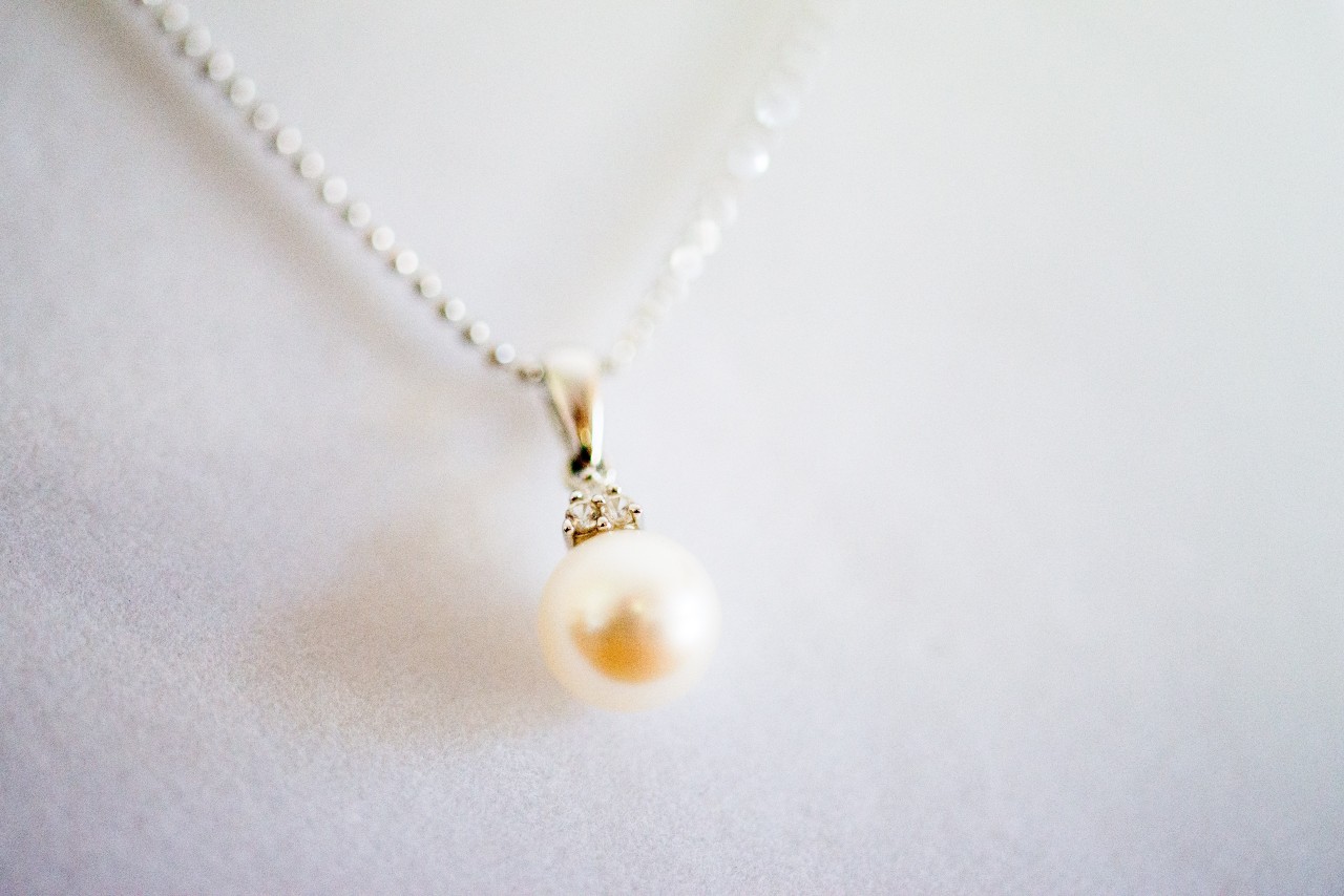 A close-up of a delicate pearl pendant necklace with a sparkling gemstone accent on a silver chain