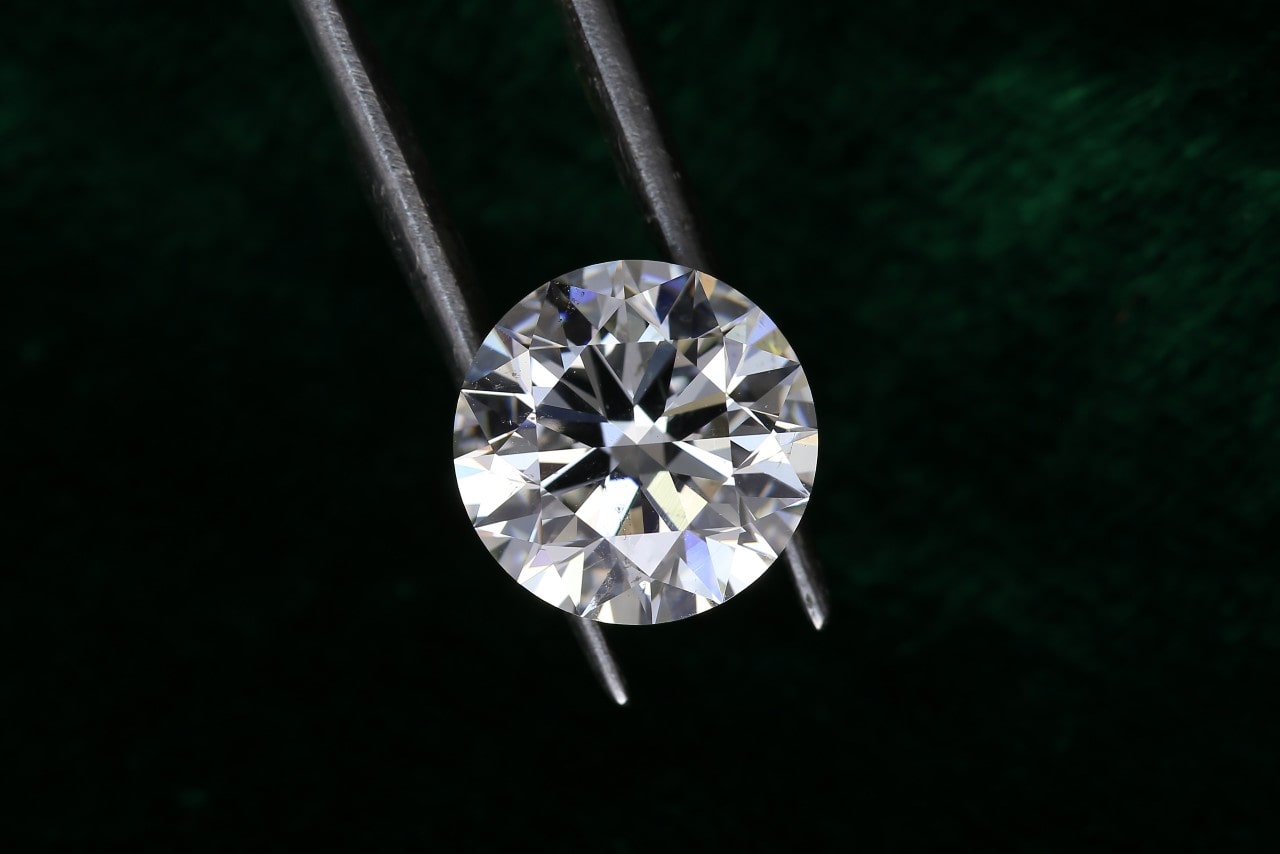 a close up of a round brilliant diamond against an emerald green background