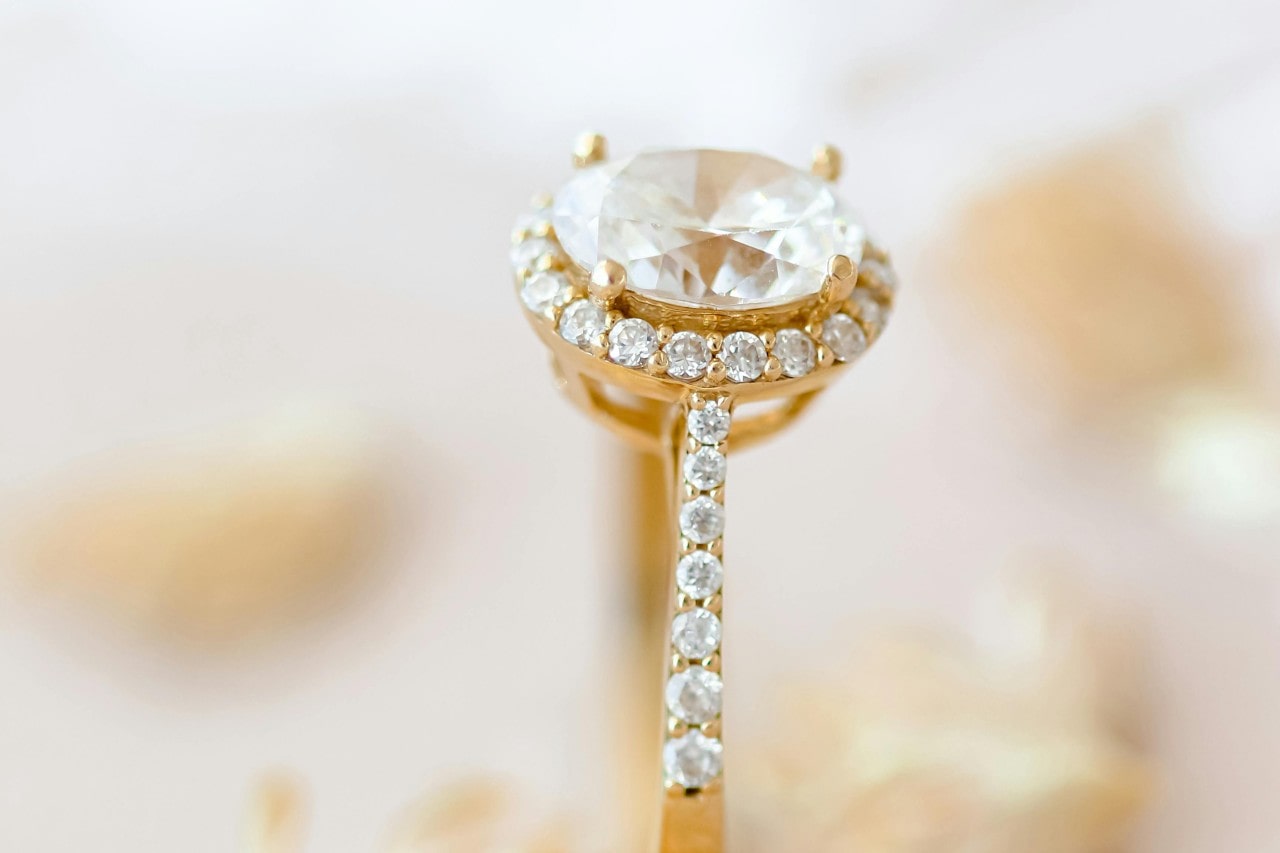 A close-up image of a yellow gold engagement ring with an oval cut engagement ring.