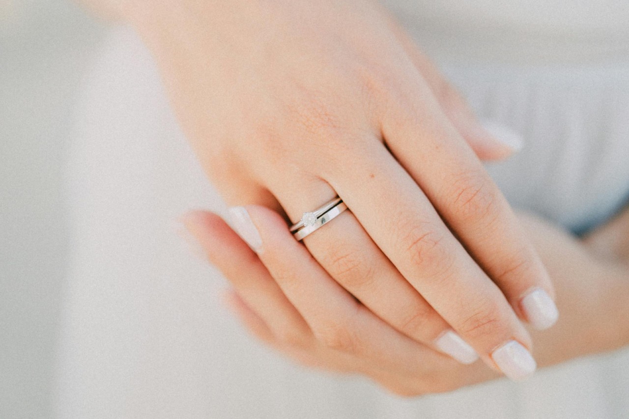 A woman’s hands, one of which is adorned with a white gold diamond ring and wedding band.