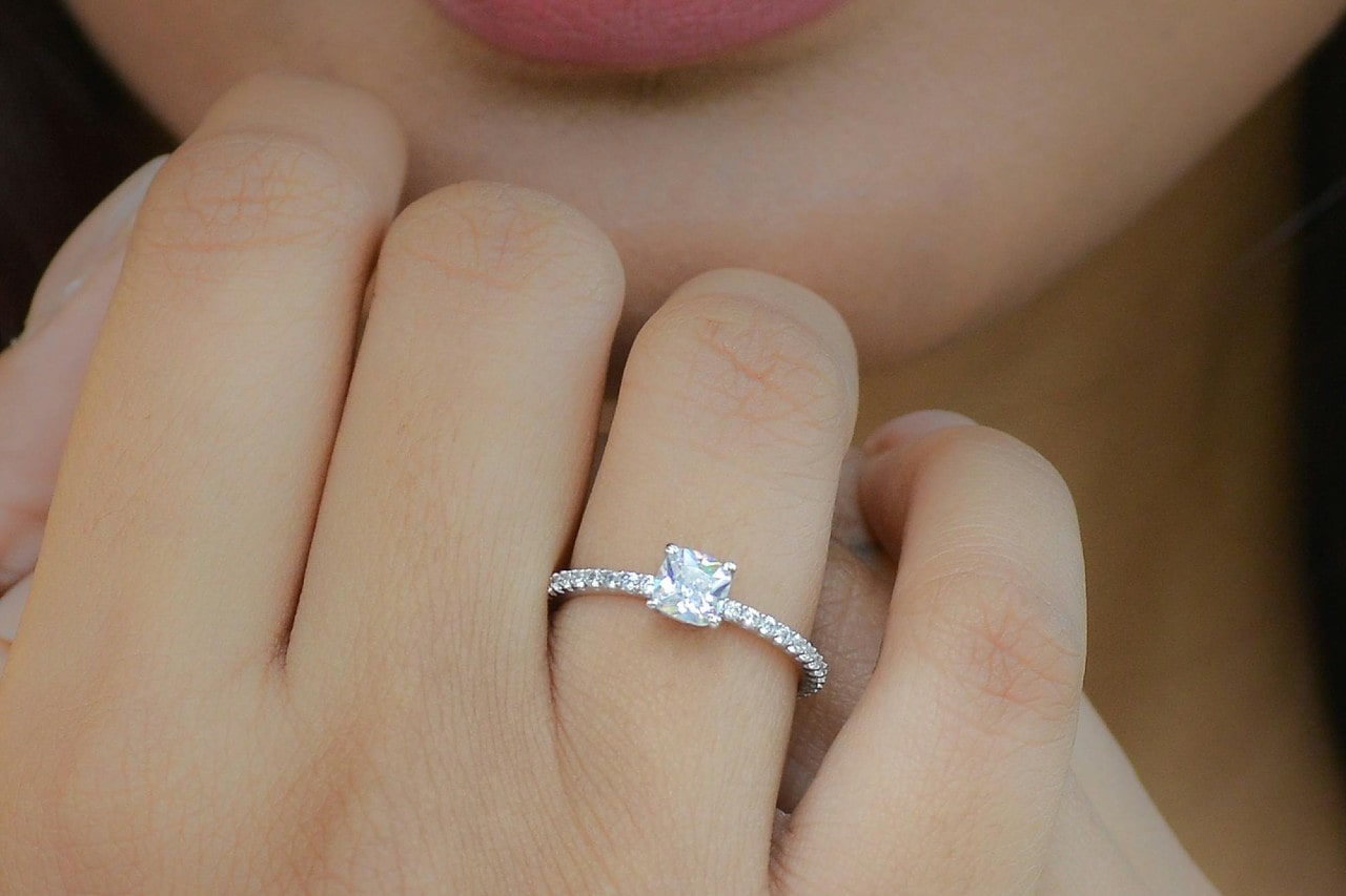 A woman wearing a platinum engagement ring, her hand raised to her chin.