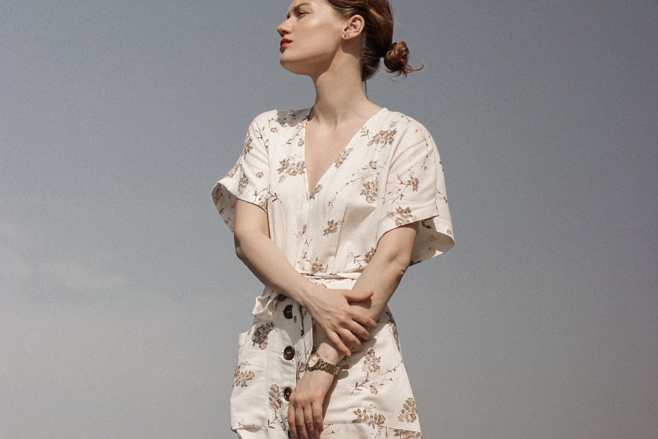 A woman in a white floral dress wearing a yellow gold watch